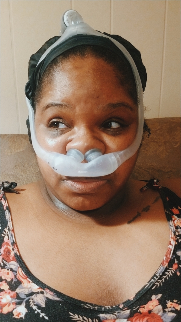 AP is pictured staring away from the camera in a nasal pillow CPAP mask.